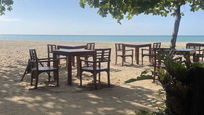 Tische und Stühle am Strand mit Blick auf das Meer