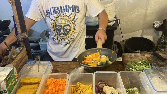 Ein Mann in einem sublimb-T-Shirt bereitet Essen in einer Pfanne