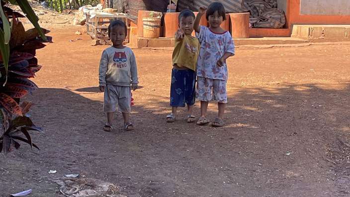 Drei kleine Kinder stehen vor einem Haus und tragen shirts mit disney-motiven