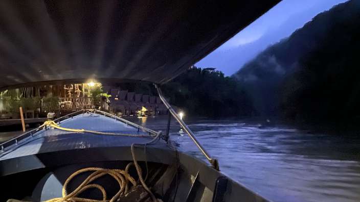 Ein Boot fährt in der Nacht auf einem Fluss