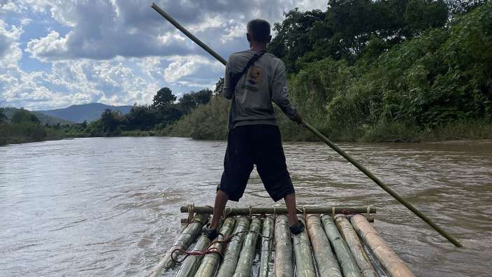 Ein Mann steht auf einem Bambusraft in einem Fluss