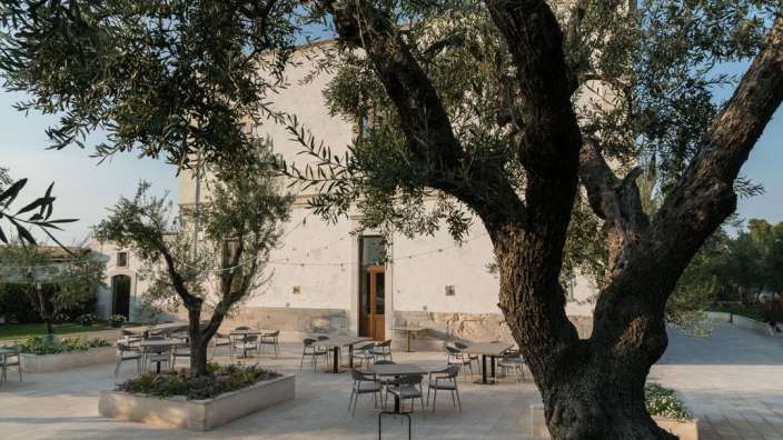 Eine Terrasse mit Tischen und Stühlen vor einem weißen Gebäude