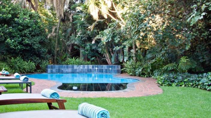 Liegestühle mit blauen und weißen Handtüchern neben einem Swimmingpool