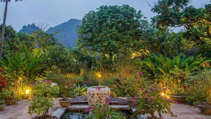 Ein Garten mit vielen Blumen und einem Brunnen