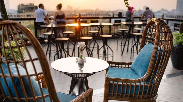 Tische und Stühle auf einer Terrasse mit Blick auf die Stadt bei Sonnenuntergang