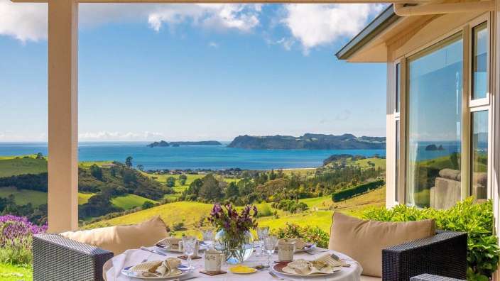 Ein Tisch mit Tellern und Gläsern auf einer Veranda mit Blick auf das Meer