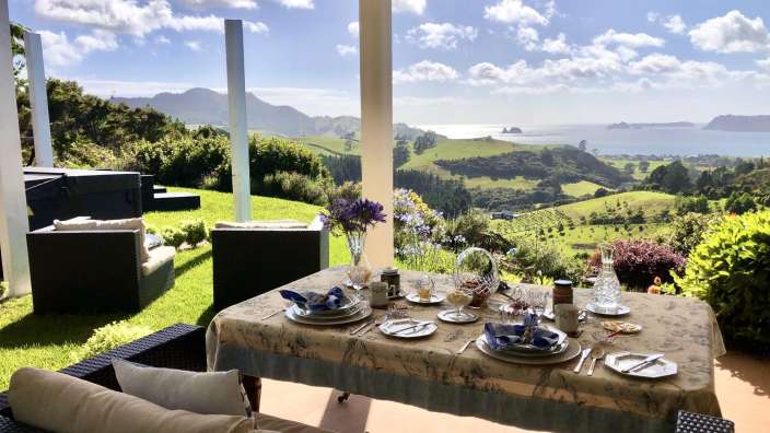 Ein Tisch mit Tellern und Gläsern auf einer Veranda mit Blick auf den Ozean