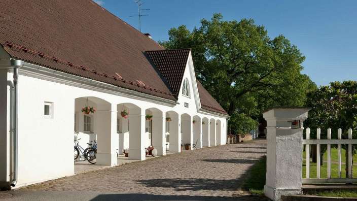 Ein weißes Gebäude mit einem braunen Dach und einem weißen Zaun