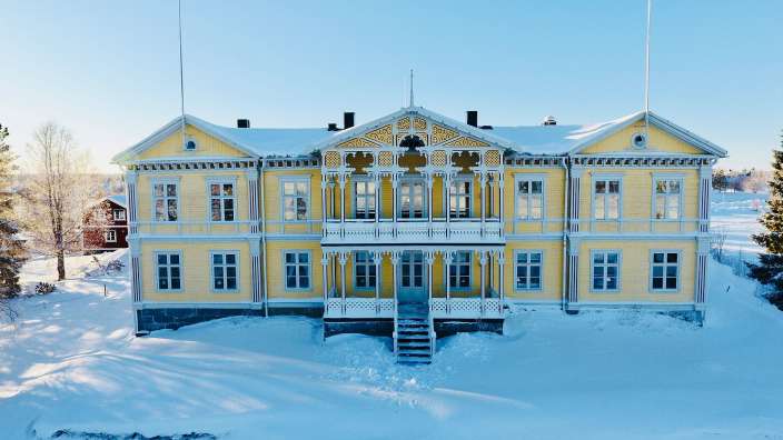 Ein großes gelbes Haus mit vielen Fenstern im Schnee