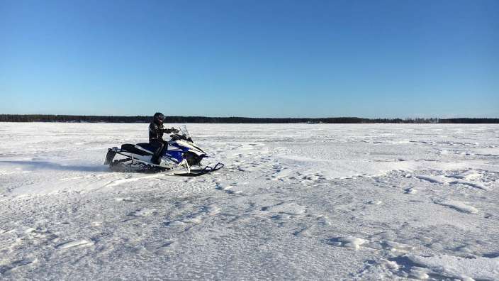 Ein Mann fährt mit einem Schneemobil auf einem schneebedeckten Feld