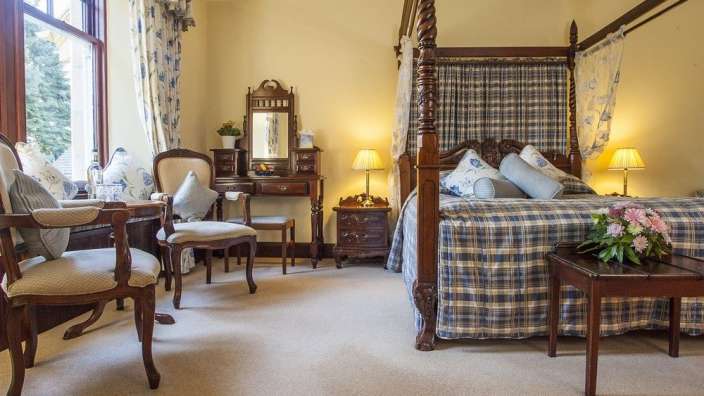 Ein Schlafzimmer mit einem Himmelbett und einem Stuhl