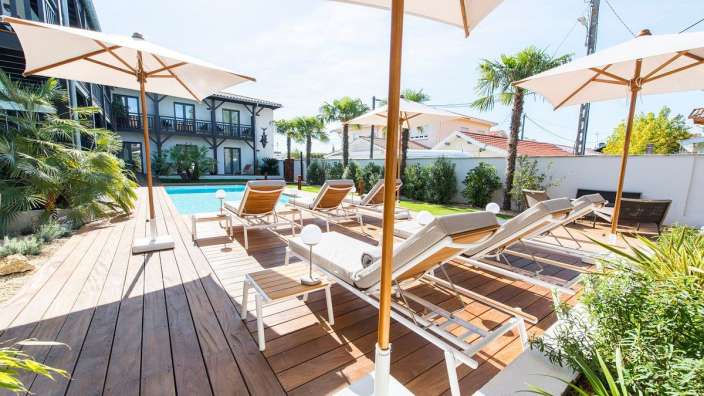 Ein Deck mit Liegestühlen und Sonnenschirmen um einen Pool