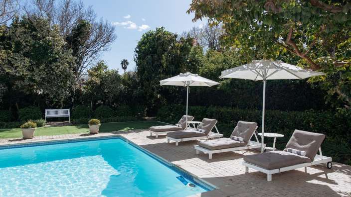 Liegestühle und Sonnenschirme umgeben einen großen Swimmingpool