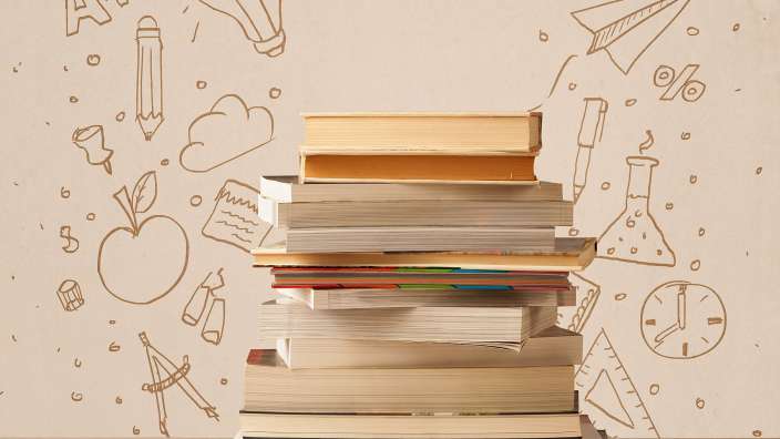 Ein Stapel Bücher steht vor einer Wand mit Handgezeichneten Symbolen