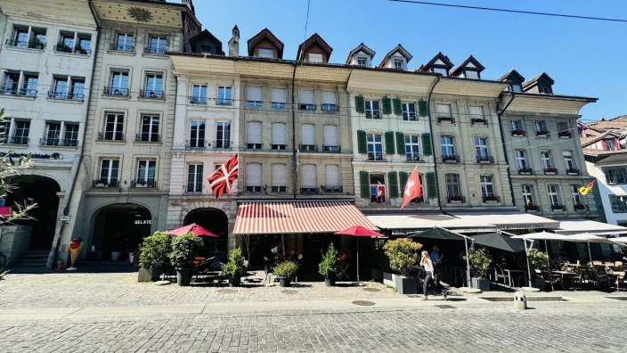 Eine Frau geht vor einem Restaurant mit roten und weißen Schirmen