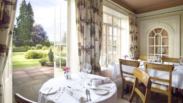 Ein Tisch und Stühle in einem Restaurant mit Blick auf einen Garten