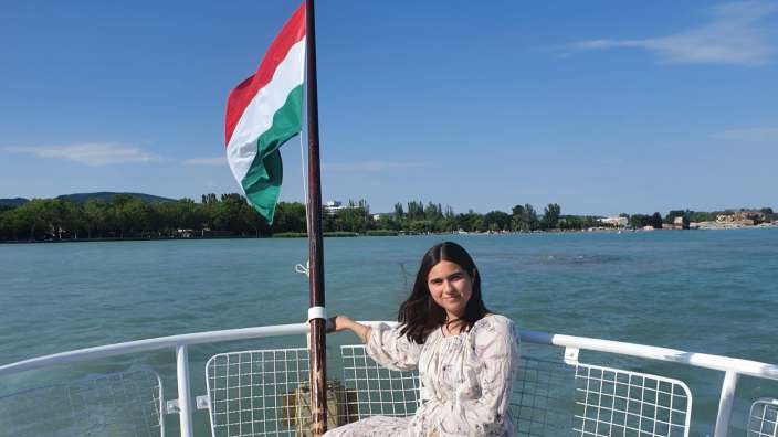 Eine Frau sitzt auf einem Boot mit einer ungarischen Flagge im Hintergrund