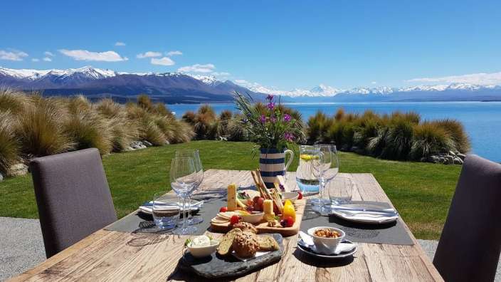 Ein Holztisch mit einem Tablett mit Essen und Weingläsern darauf