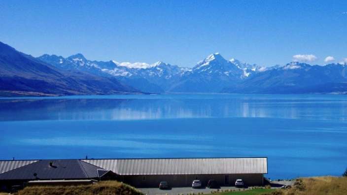 Ein Gebäude neben einem See mit Bergen im Hintergrund
