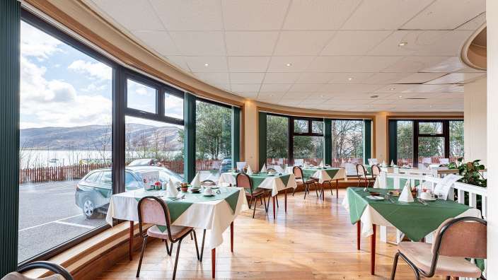 Tische und Stühle in einem Restaurant mit vielen Fenstern