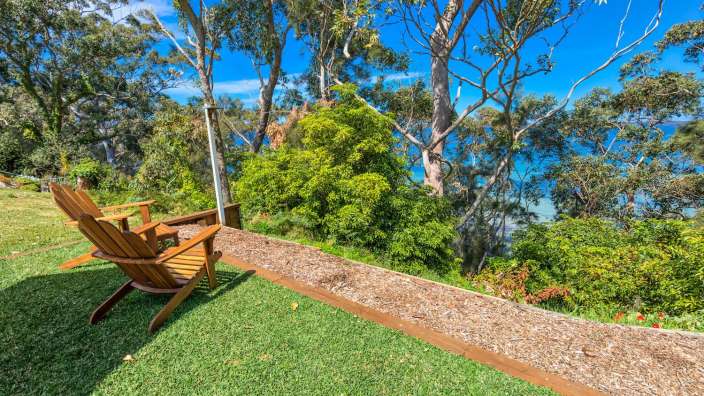 Ein Holzstuhl sitzt auf einer Wiese mit Blick auf den Ozean