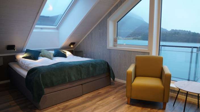Ein Schlafzimmer mit einem Bett und einem Stuhl mit Blick auf einen See