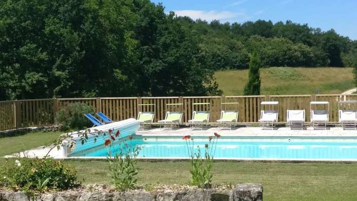Liegestühle stehen um einen großen Swimmingpool an einem sonnigen Tag