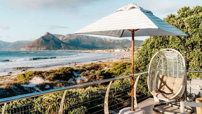 Ein weißer Stuhl steht auf einem Balkon mit Blick auf den Strand