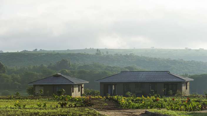 Zwei Häuser stehen auf einem Feld mit Bäumen im Hintergrund