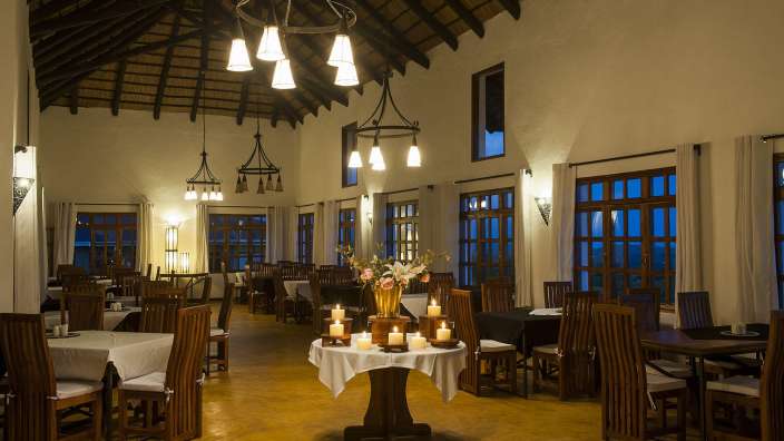 Ein Esszimmer mit vielen Tischen und Stühlen und einem Tisch mit Kerzen darauf