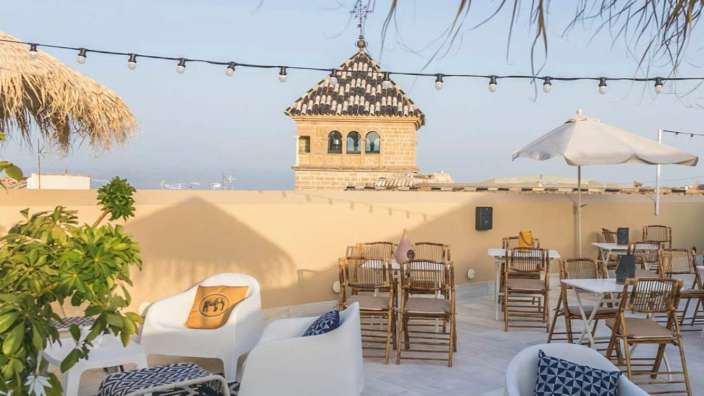 Eine Terrasse mit Stühlen und Tischen mit einem Turm im Hintergrund