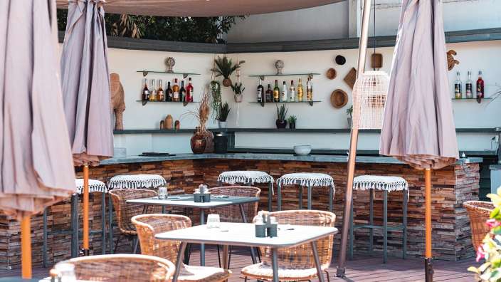 Tische und Stühle in einem Restaurant mit einer Bar im Hintergrund