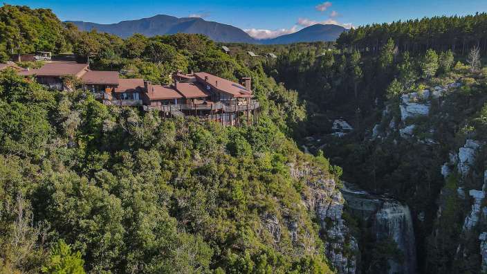 Ein großes Haus sitzt auf einer Klippe mit Blick auf einen Fluss
