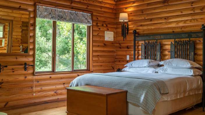 Ein Schlafzimmer in einem Blockhaus mit einem Bett und einem Fenster