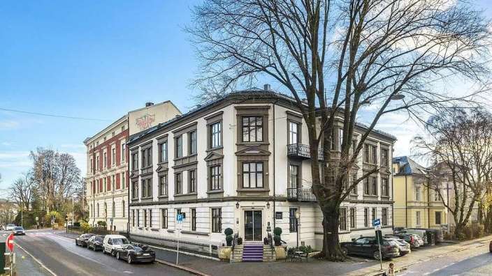 Eine Frau geht an einem Straßenkreuz vor einem großen weißen Gebäude