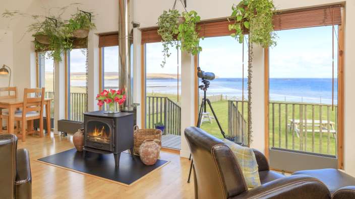 Ein Wohnzimmer mit vielen Fenstern und einem Holzofen