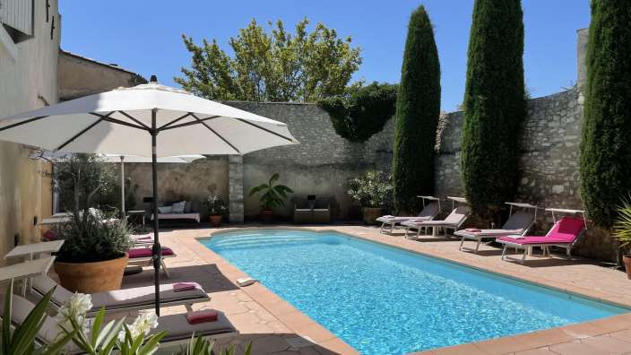 Ein großer Swimmingpool umgeben von Liegestühlen und Sonnenschirmen