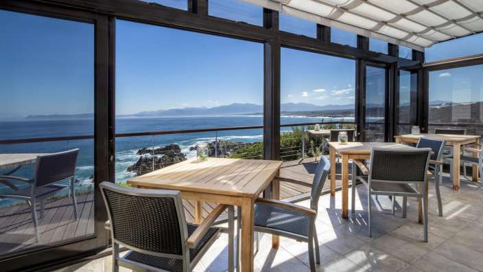 Tische und Stühle auf einer Terrasse mit Blick auf den Ozean