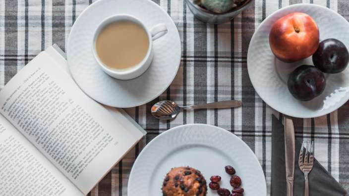 Ein Buch liegt auf einem Tisch neben einer Tasse Kaffee