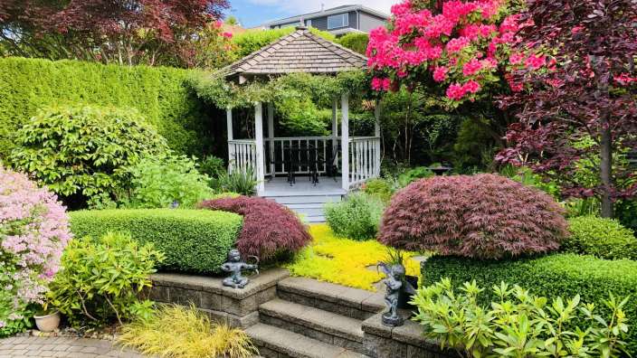 Ein Garten mit einem weißen Pavillon und vielen Blumen