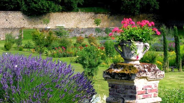 Ein Blumentopf steht auf einem Ziegelpfosten in einem Garten