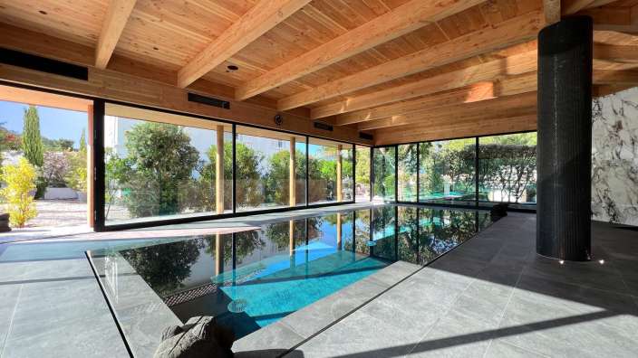 Ein großer Swimmingpool in einem Haus mit vielen Fenstern