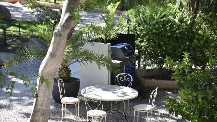 Ein Tisch und Stühle in einem Garten neben einem Grill