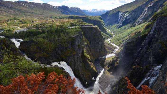 Ein Wasserfall mitten in einem Tal mit Bergen im Hintergrund
