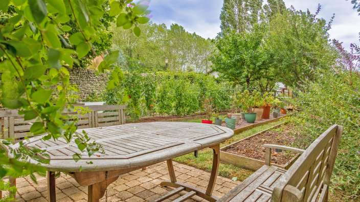 Ein Tisch und Stühle in einem Garten mit vielen Pflanzen