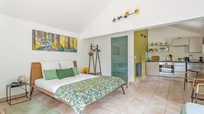 Ein Schlafzimmer mit einem Bett und einer Küche dahinter