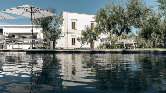 Ein Pool mit einem weißen Haus im Hintergrund