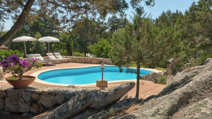 Ein großer Pool mit Liegestühlen und Sonnenschirmen umgeben