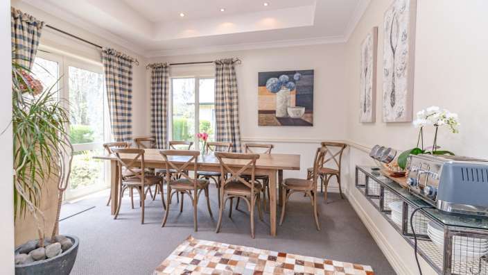 Ein Esszimmer mit einem Tisch und Stühlen und einem Gemälde an der Wand