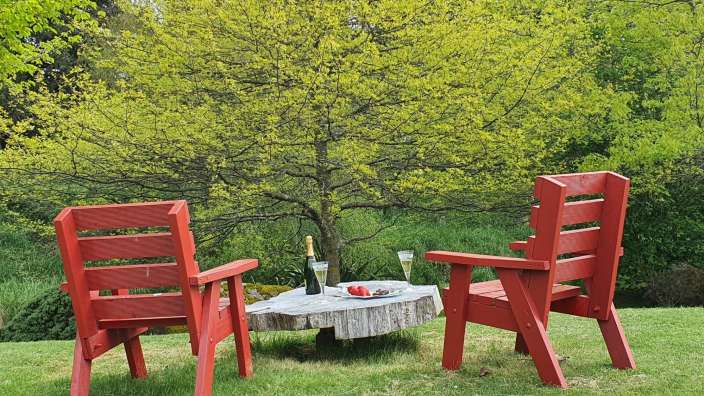 Zwei rote Stühle sitzen neben einem Tisch mit einer Flasche Champagner darauf